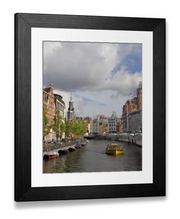 Framed Print : A boat travel down a canal near the flower market with the steple of Muntplein