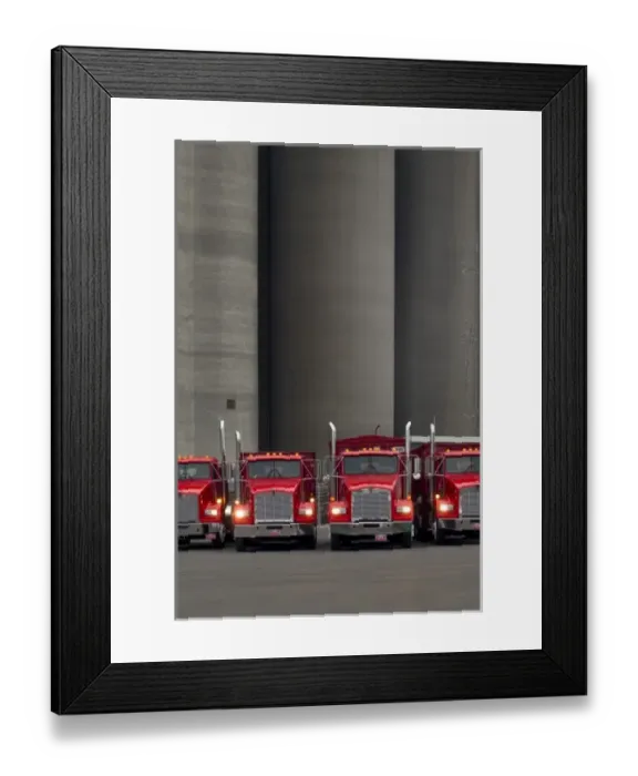 Framed Print : Four red trucks with lights turned on lined up in front of tall concrete silos in Framed Print : Four red trucks with lights turned on lined up in front of tall concrete silos in