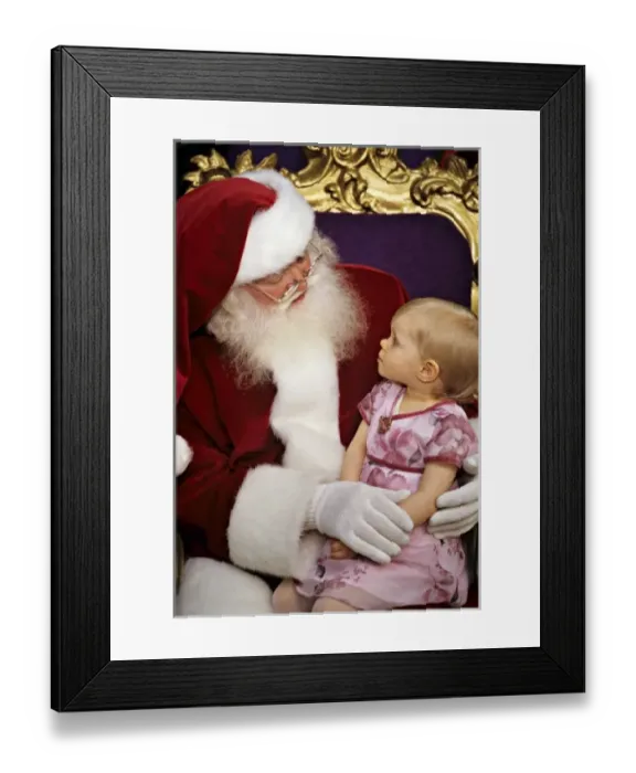 Framed Print : USA. Two year old girl sits on Santa Claus lap (MR) Framed Print : USA. Two year old girl sits on Santa Claus lap (MR)