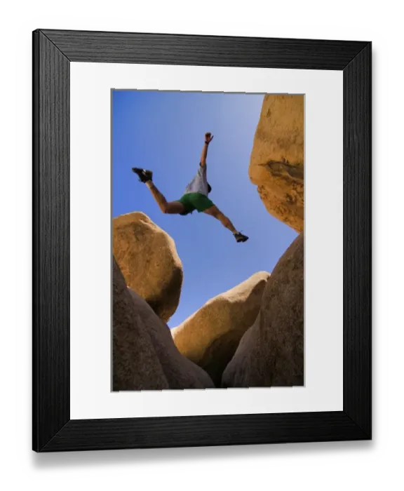 Framed Print : USA, California, Joshua Tree National Park. A male hiker leaps across a boulder. (MR)