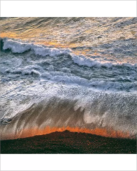 USA, California, Big Sur. Breaking surf catches the late fiery light of sunset at