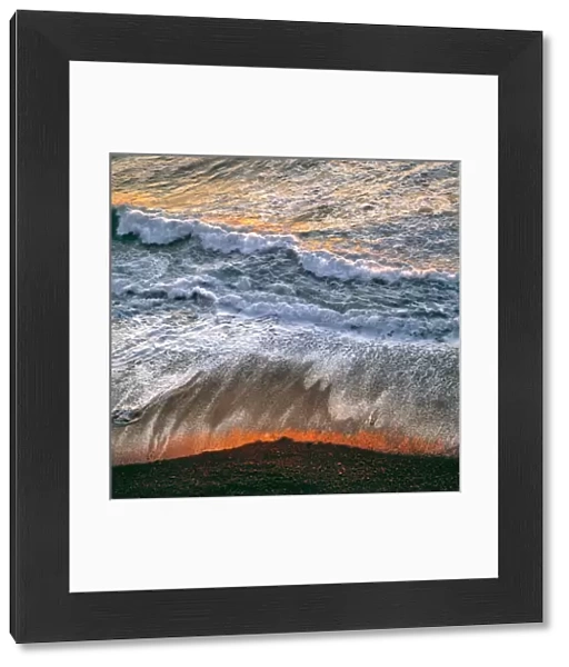 USA, California, Big Sur. Breaking surf catches the late fiery light of sunset at