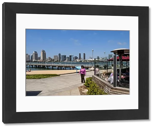 Woman walking on pavement with scenic of skyline of San Diego from Coronado Island