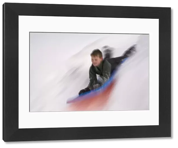 United States, Washington, Crystal Mountain, boy on sled in motion (MR)
