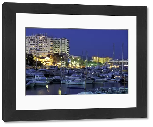 Spain, Balearics, Ibiza, Sant Antoni de Portmany. Evening view of city and marina