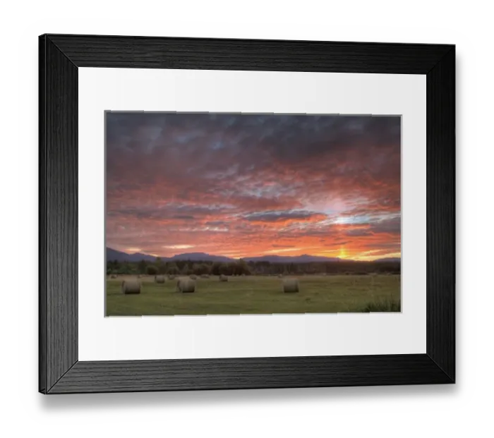 Framed Print : Vivid sunrise clouds over hay bales in field and the Whitefish Mountain Range in Montana