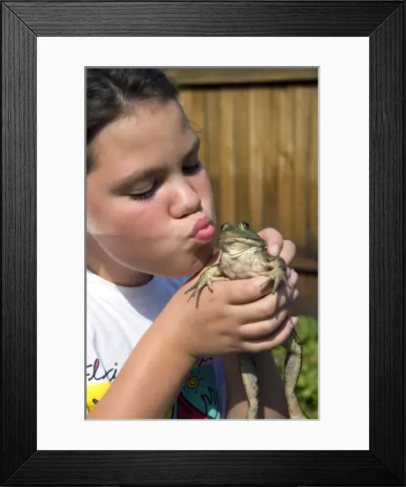 Framed Print : 11 year old girl kissing a bullfrog in Boise, Idaho. (MR)
