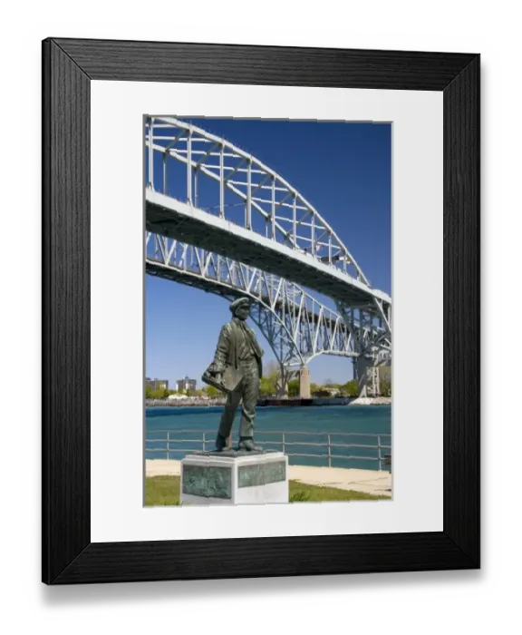 Framed Print : A statue of Thomas Edison by local artist Mino Duffy sits below the Blue Water Bridge along the St