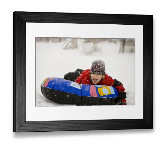 Framed Print : A young boy sledding on a snow tube during a snowstorm in Portsmouth, New Hampshire Framed Print : A young boy sledding on a snow tube during a snowstorm in Portsmouth, New Hampshire
