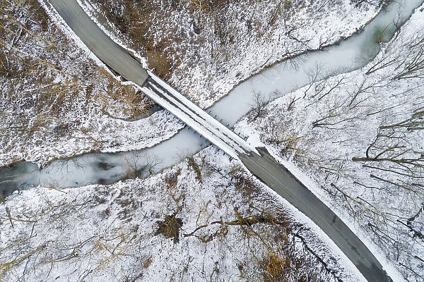 Aerial view of winter forest, bridge, and creek Stephen A