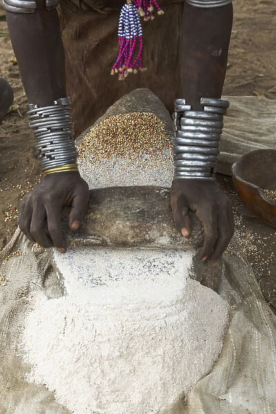 Africa, Ethiopia, Southern Omo, Karo Tribe. Woman grinding grain into flour with stone