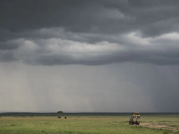Africa, Kenya, Msai Mara National Reserve. Storm clouds over tourist vehicle. Credit as
