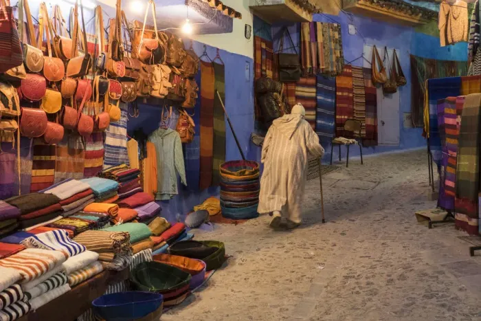 Framed Print : Africa, Morocco. An elderly man walks past tourist shops along a street in the blue Framed Print : Africa, Morocco. An elderly man walks past tourist shops along a street in the blue