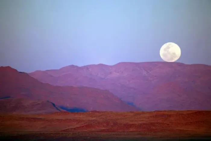 Framed Print : Africa, Namibia, Sossusvlei. A full moon rests on the crest of foothills in the NamibRand