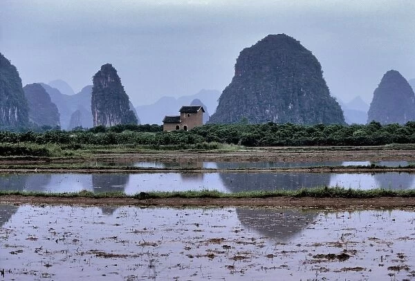 Asia, China, Guilin. A lone house oversees ponds by the karst formations near Guilin