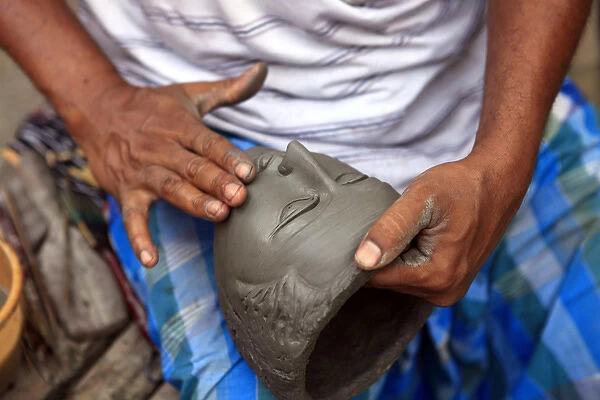 Asia, India, Calcutta. Sculptor hands work on face the potters village of Kumartuli
