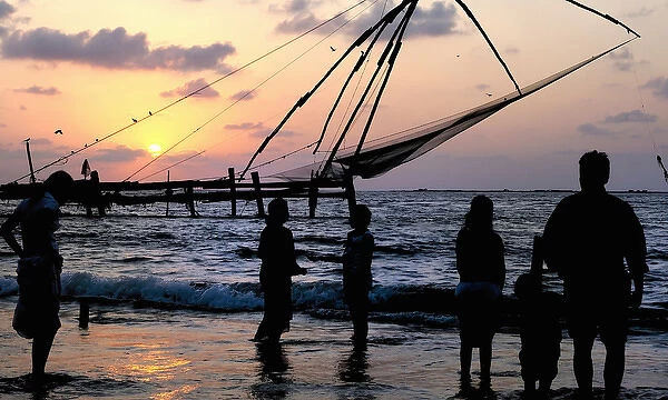 Asia, India, Kerala, Kochi (Cochin). A silhouette of people and a Chinese fishing net