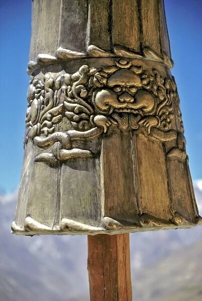 Asia, India, Ladakh, Karsha. A close-up of a strikingly carved brass figure hides the Himalayas