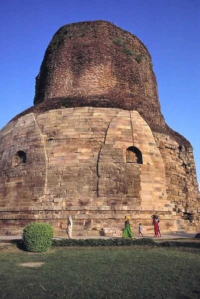 Asia, India, Sarnath. Diminished figures walk in front of the pink-stoned Dhamekh Stupa