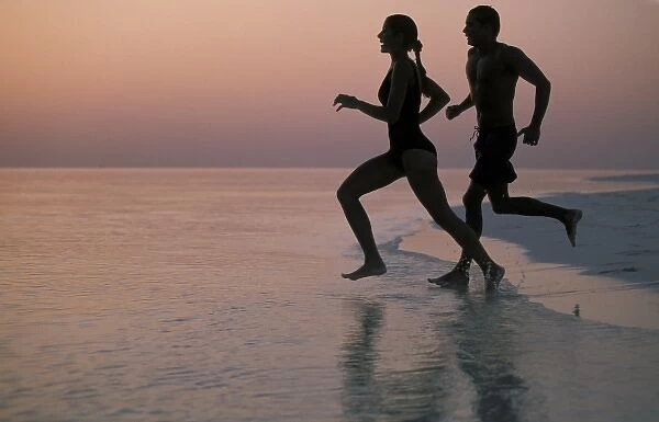 Asia, Maldives. Couple running on beach (MR)