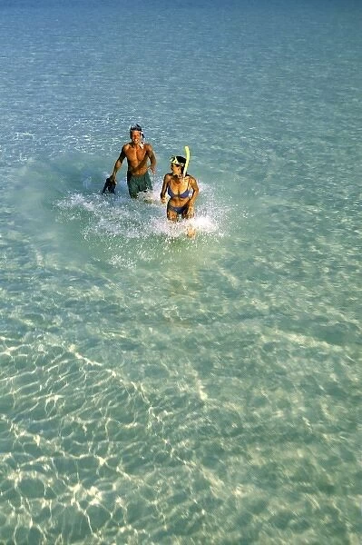 Asia, Maldives. Couple running through waves with diving gear (MR)