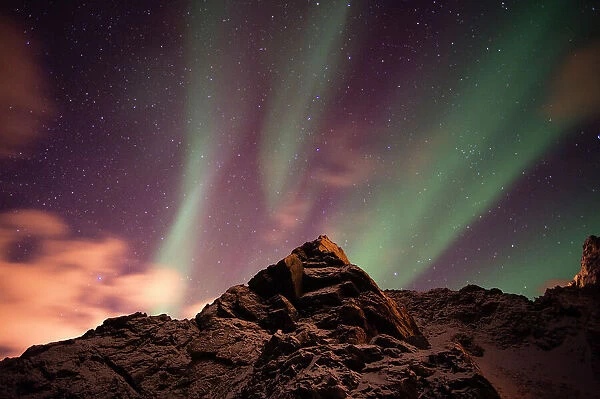 An aurora borealis behind a mountain peak in Andenes. Andenes, Vesteralen Islands, Nordland, Norway