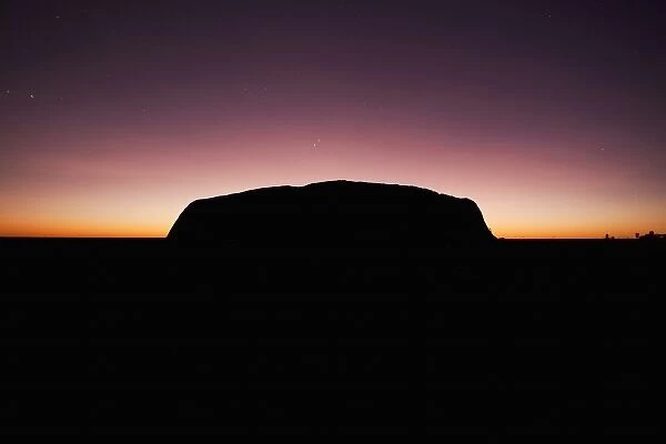 Australia, Northern Territory, Uluru-Kata Tjuta National Park. Rising sun silhouettes