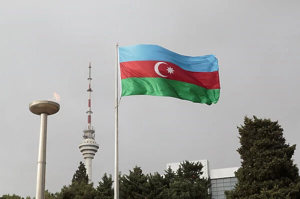 Azerbaijan, Baku. An Azerbaijan flag waves near a memorial flame and the Baku TV tower