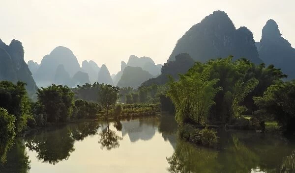 Bamboo and karst formations reflected in small pond along the Yulong River, China