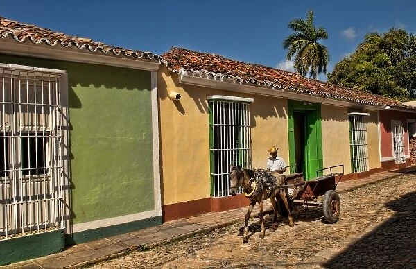 Beautiful homes in Colonial city of Trinidad Cuba with man riding horse cart on cobblestone