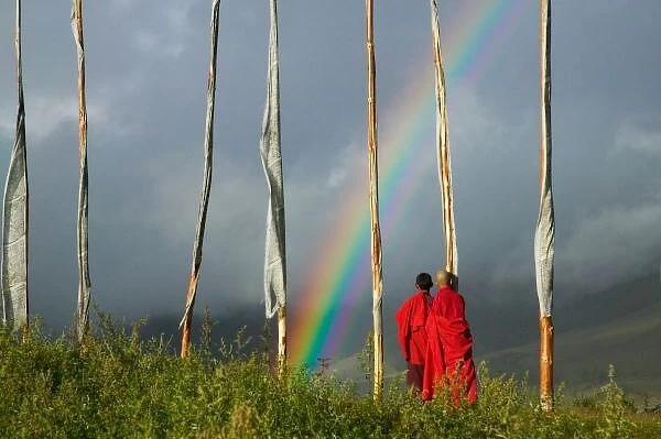 Bhutan, Gangtey village, Rainbow over two monks with praying flags in the Phobjikha Valley