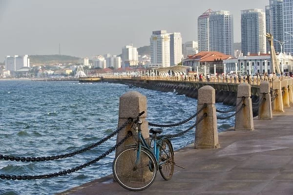 Bicycle at waterfront with Yantai city skyline, Shandong Province, China