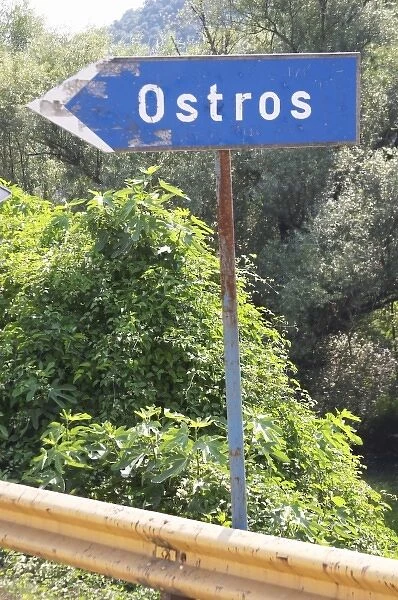 Blue rusty Road side sign pointing left saying Ostros. Near Dupilo, Golubovic Montenegro