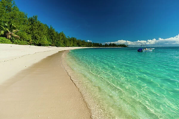A boat anchored off the shore of a pristine tropical beach. Denis Island, Seychelles