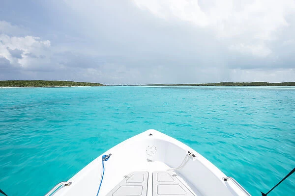 A boat drives through clear aquamarine waters near Staniel Cay, Exuma, Bahamas