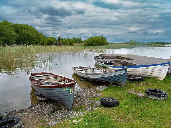 Boats await skippers on Lough Carra, County Mayo, Ireland. Shrine watches over the fishermen