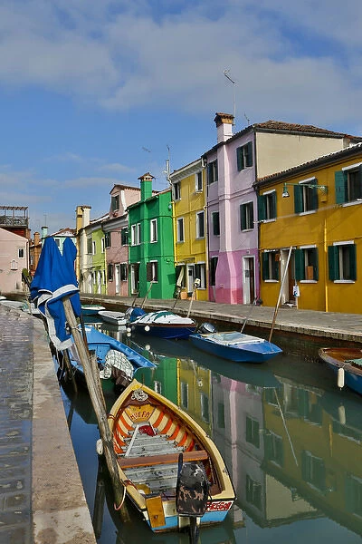 Boats docked along canal with the Colorful Homes of Burano, Italy