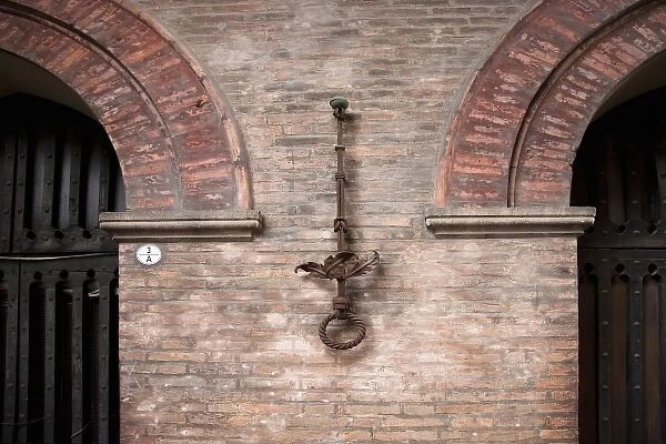 Bologna, Emilia-Romagna, Italy - An ornate iron ring is mounted on a brick wall