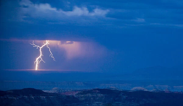 A bolt of lightning strikes the Utah desert as a rain storm moves across the landscape