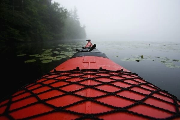 The bow of a kayak on a foggy morning on Mirror Lake in Woodstock, NH. Hubbard Brook