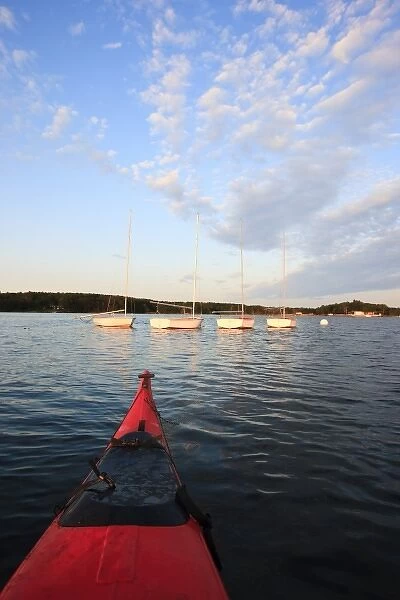 The bow of a kayak and moored sailboats in Portsmouth Harbor in Portsmouth, New Hampshire