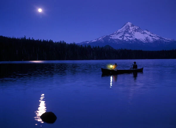 Two boys in canoe with lantern at night on Lost Lake with Mt Hood in the background