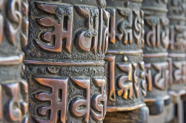 Bronze prayer wheels carved with Buddhist scripture, Swayambhunath, Kathmandu, Nepal