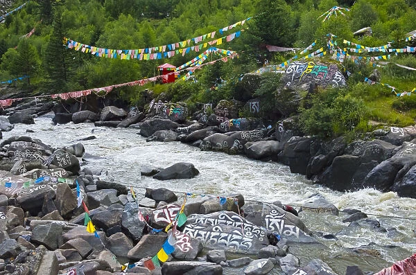Buddhist words painted on rocks and praying flags by the river, Tagong, western Sichuan