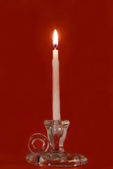 Framed Print : Burning candle in a glass candle holder on red background