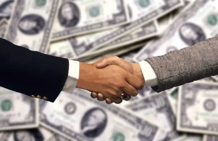 Framed Print : Two businessmen, in front of US currency, shaking hands to close a deal