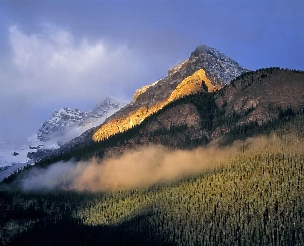 Canada, Alberta, Banff NP. Sunrise strikes the flank of the Canadian Rockies as clouds