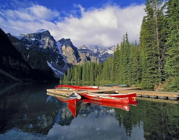 Canada, Alberta, Moraine Lake. The glassy surface of Moraine Lake mirrors red canoes