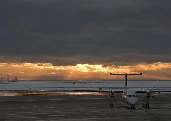 Canada, British Columbia, Vancouver. Dash 8 aircraft with sun lighting distant clouds