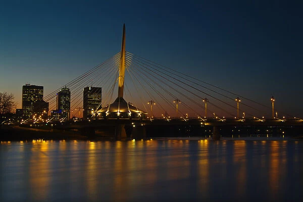 Canada, Manitoba, Winnipeg. Esplanade Riel bridge and city skyline reflected in Red River at dusk